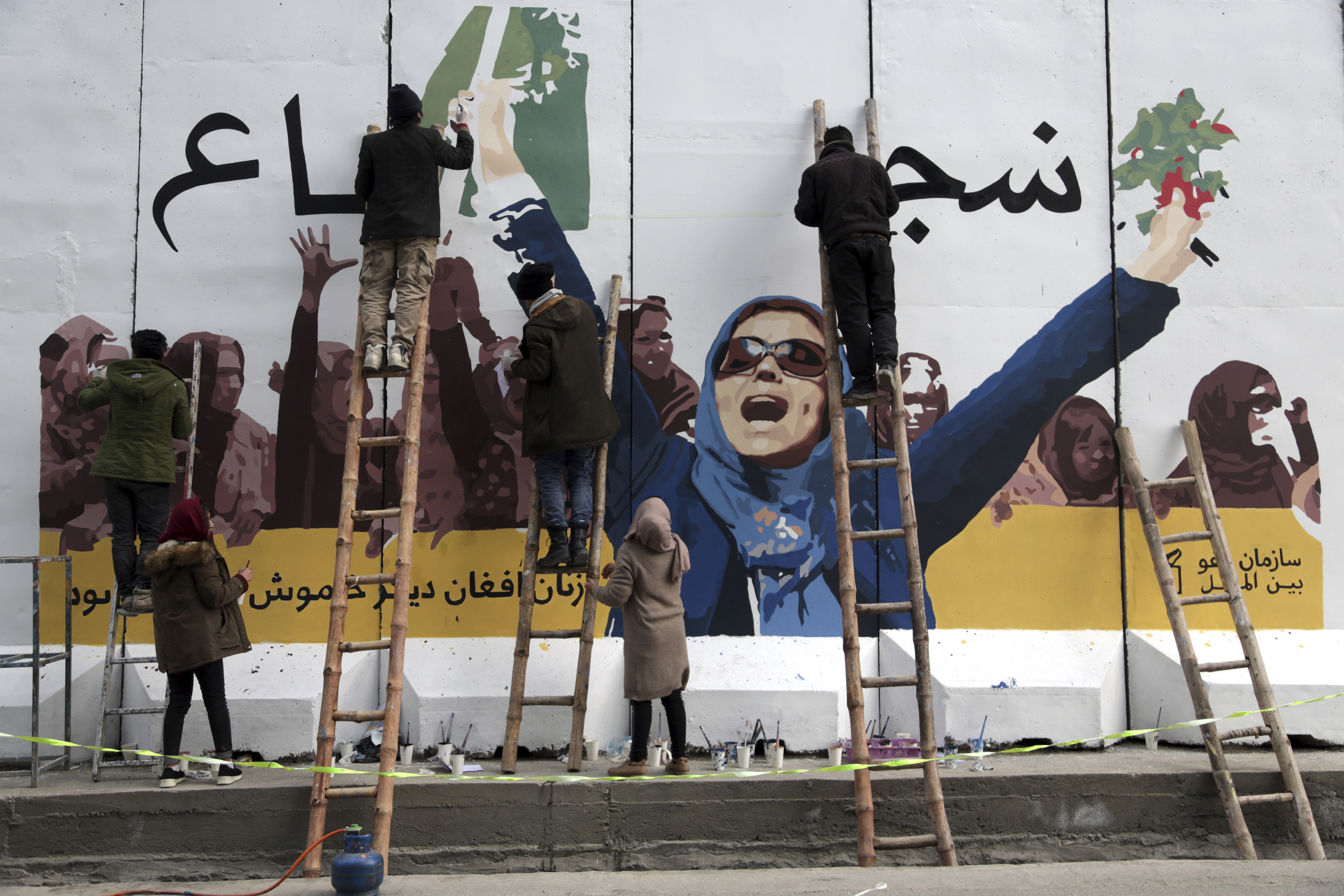 Independent Afghan artists draw a graffiti on a barrier wall of the Ministry of Women's Affairs to mark International Women's Day in Kabul, Afghanistan, Friday, March 8, 2019. (AP Photo/Rahmat Gul)