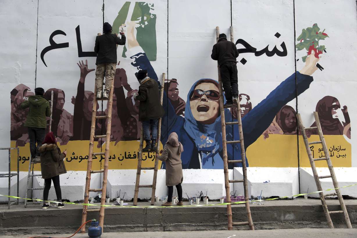 Independent Afghan artists draw a graffiti on a barrier wall of the Ministry of Women's Affairs to mark International Women's Day in Kabul, Afghanistan, Friday, March 8, 2019. (AP Photo/Rahmat Gul)