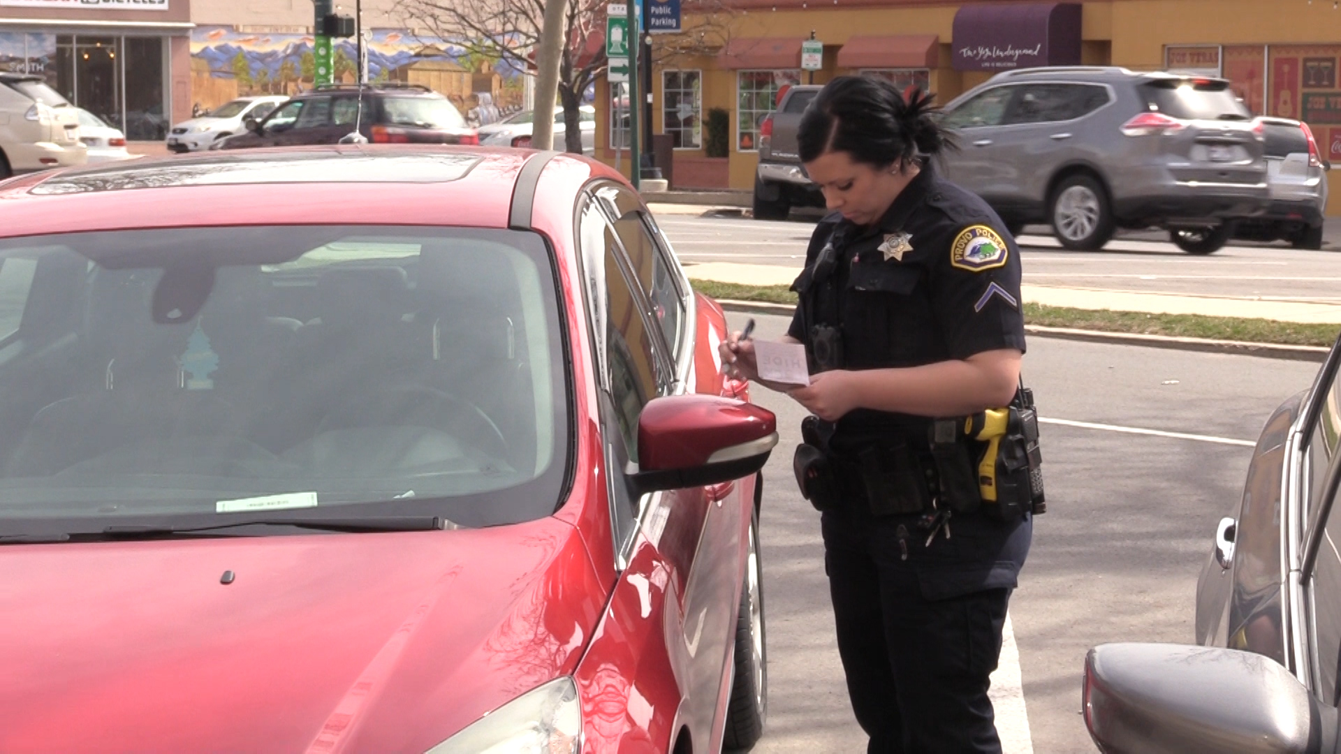 Provo police officer Brooke Fox leaves a "Hide. Lock. Keep." card on the window of a parked car. She and her fellow officers hope the card will remind property owners to keep valuable items hidden, and help reduce crime. (Photo: Sam Penrod, KSL TV)