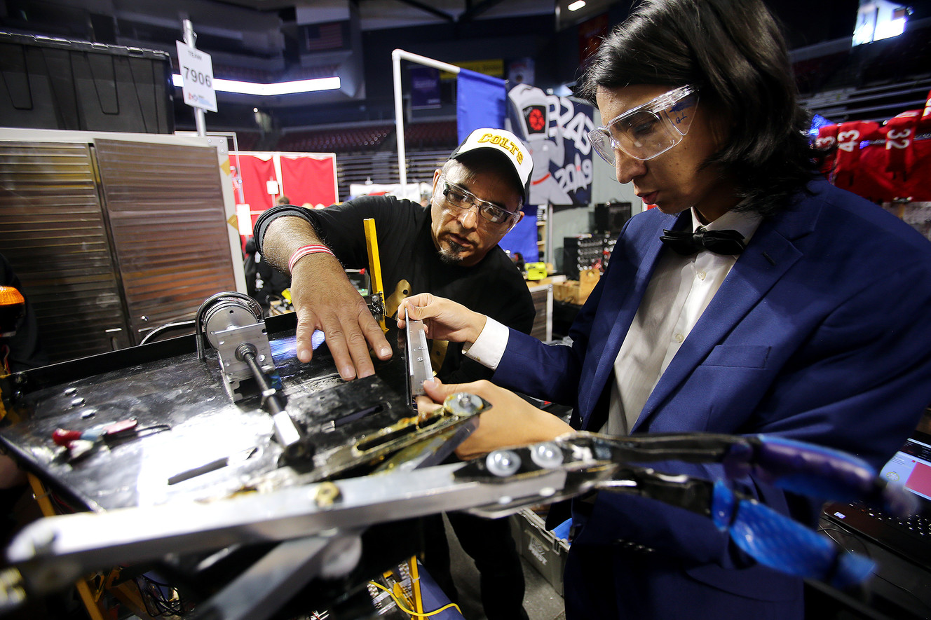 Teacher Yuri Perez works with Mahammad Noori and students from Cottonwood High School as they workout issues with their robot as they compete in the First Robotics Competition Utah Regional event at the Maverik Center in West Valley City, Utah, on Friday, March 29, 2019. (Photo: Scott G Winterton, KSL)