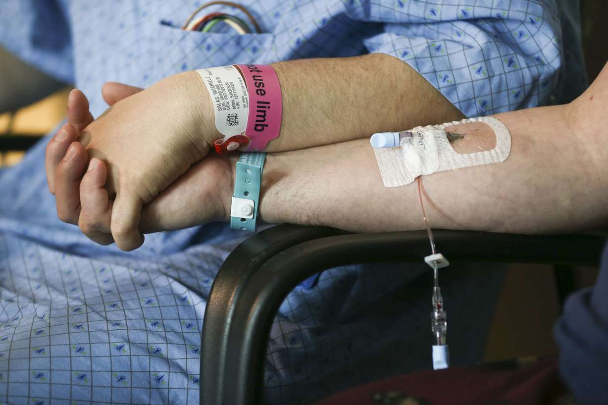 Kidney donor Matthew Thompson holds the hand of Mitchell Salas, left, who received his kidney two days earlier at Intermountain Medical Center in Murray on Friday, March 29, 2019. Thompson and Salas met for the first time at the hospital after their surgeries. (Photo: Silas Walker, KSL)