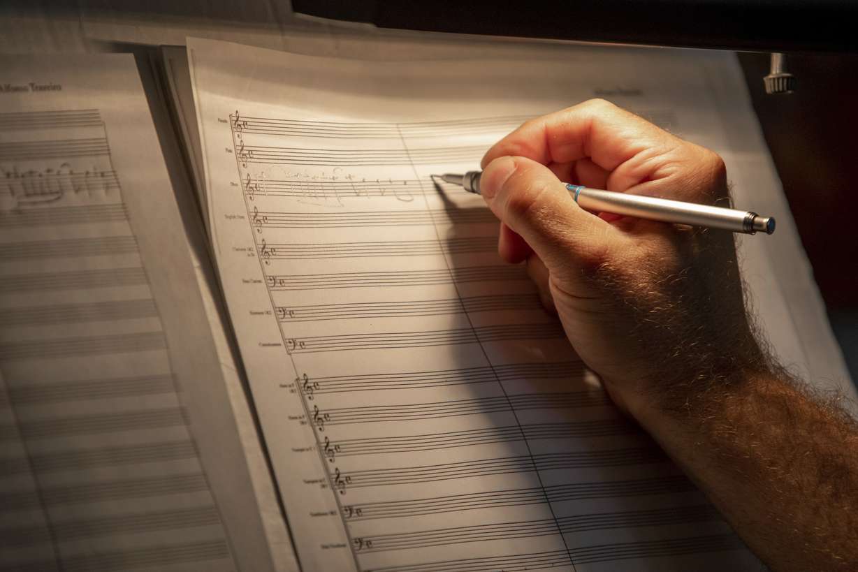 FILE- In this Thursday, July 19, 2018 photo, classical composer Alfonso Tenreiro works on an orchestral composition at his piano in his home in Ogden, Utah. (Benjamin Zack, Standard-Examiner via AP, File)