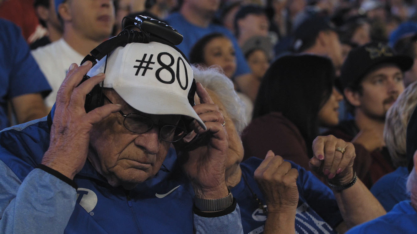 Verle Tolley momentarily lifts off his headphones to speak with his family during a break in the action during BYU's last home game against Utah in 2017. (Photo: James Terry for KSL.com)