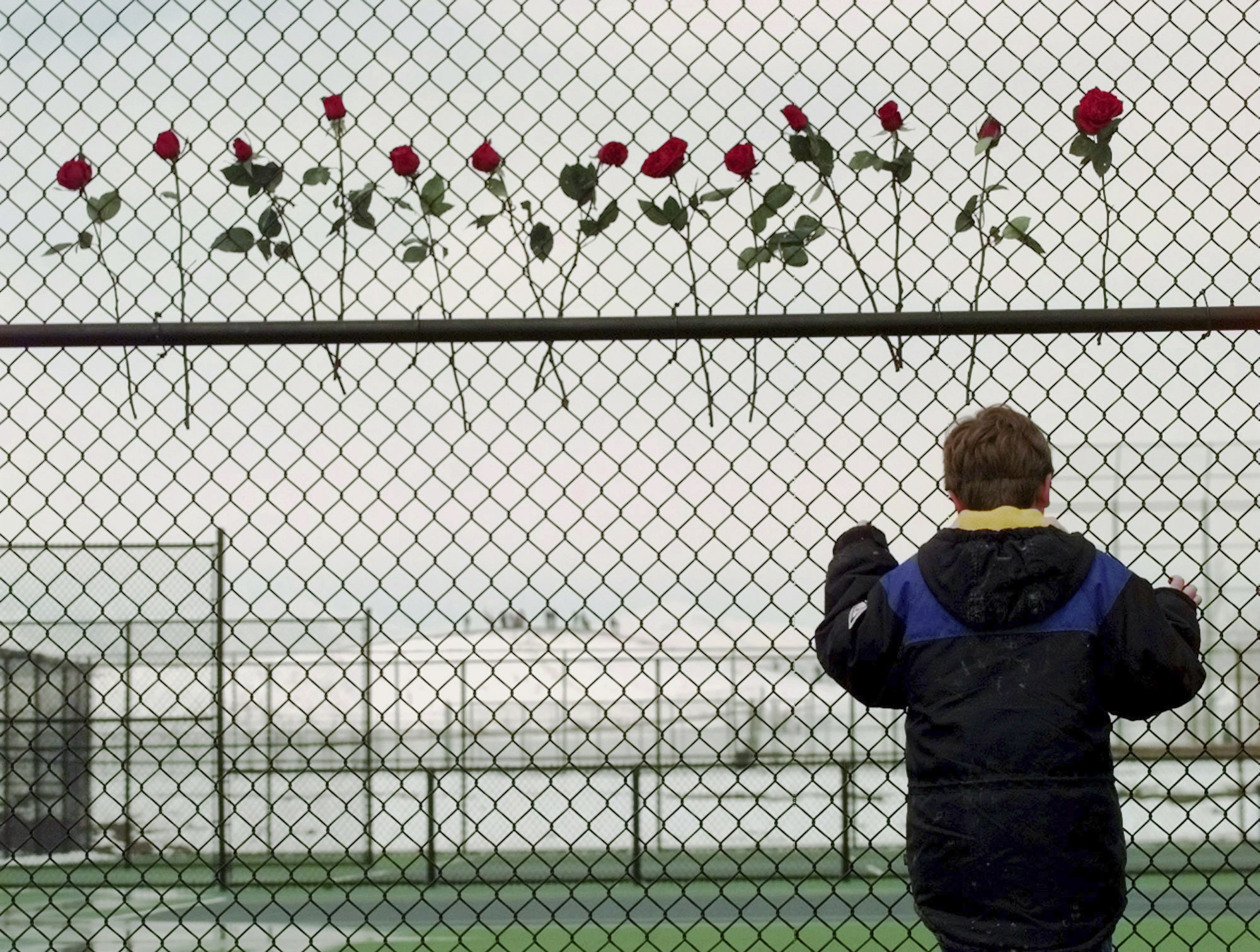 FILE - In this April 24, 1999, file photo, a boy looks through the fence at the Columbine High School tennis courts in Littleton, Colo. Thirteen roses were placed on the fence in remembrance of the 13 people killed by two gun wielding students at the school. (: Photo: Eric Gay, AP Photo, File)