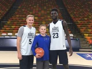 Tate Erickson poses for a photo with Utah State players Sam Merril and Neemias Queta. (Photo: Courtesy: Erickson family)