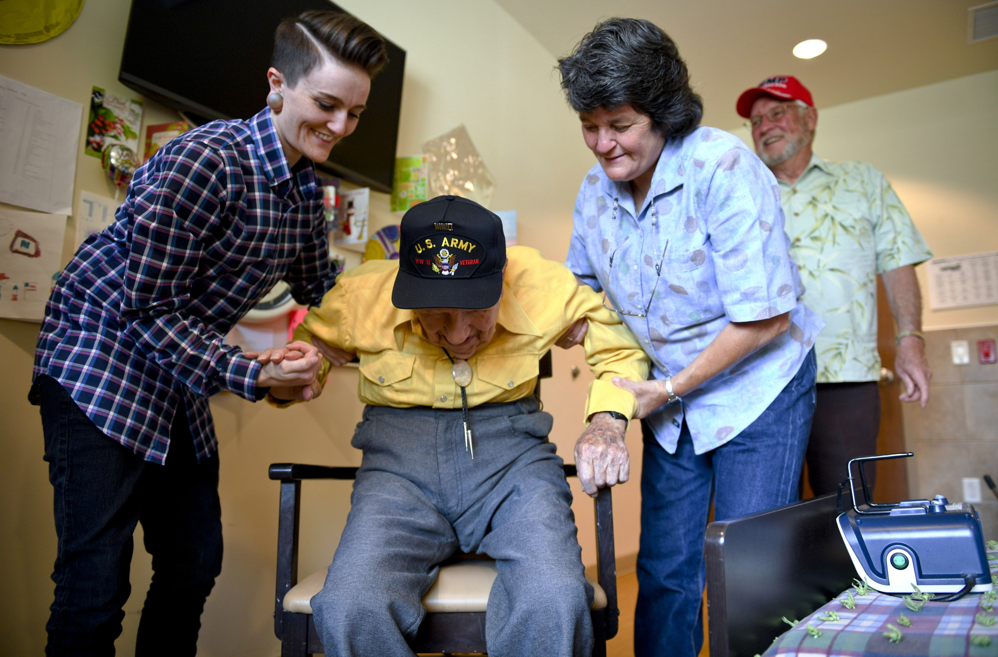 In this Monday, May 6, 2019, photo, John R. Frey, 100 years old and a U.S. Army veteran, is helped out of a chair by his daughter, Janice Carlson, right, and granddaughter, Kara Carlson, as his son-in-law, Gary Carlson, stands by at the Mervyn Sharp Bennion Central Utah Veterans Home in Payson, Utah. Frey will turn 101 on June 7 of this year. (Isaac Hale/The Daily Herald via AP)