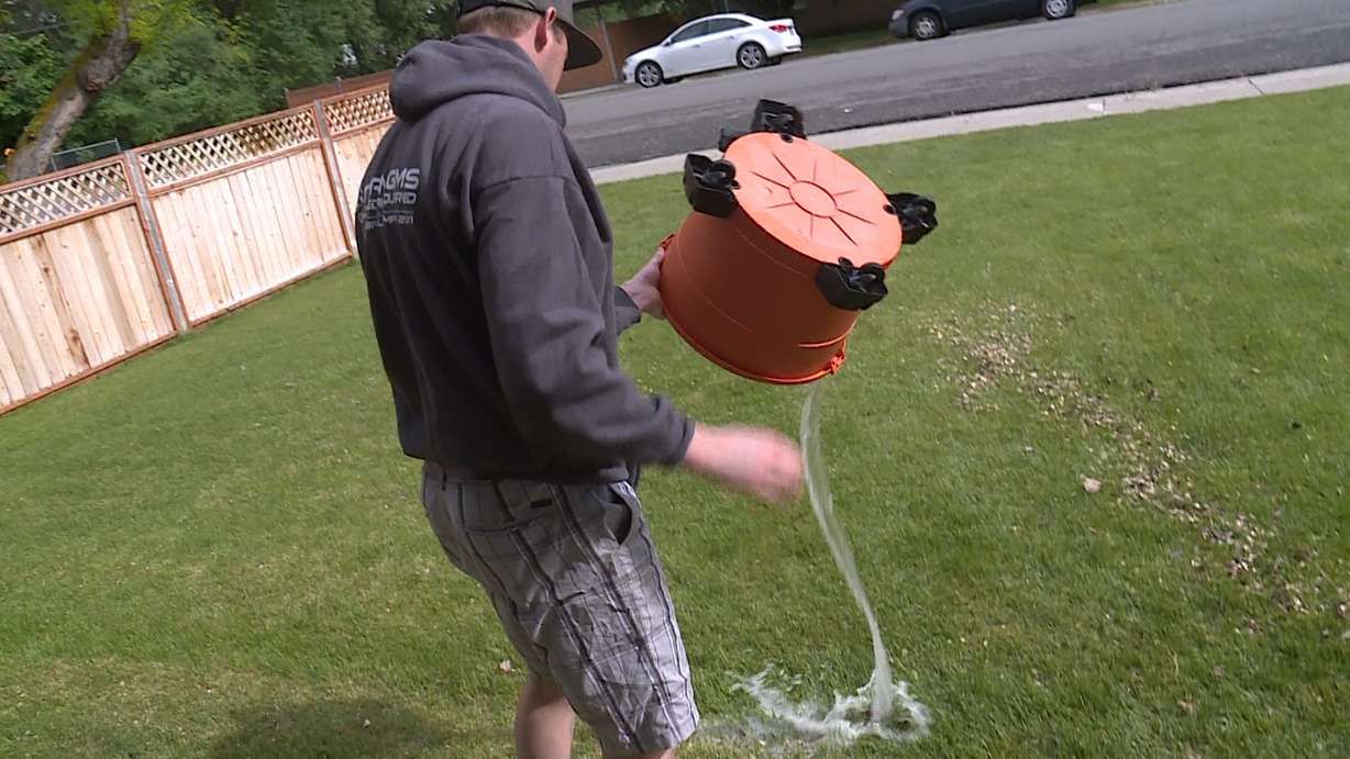 Brian Stewart dumps a bucket of water into his yard while trying to clean out his flooded basement Friday, May 17, 2019. Several homes in Stewart's neighborhood, near 765 N. Center St. in Lehi, were flooded when the banks of Dry Creek overflowed early that morning. (Photo: Ray Boone, KSL TV)