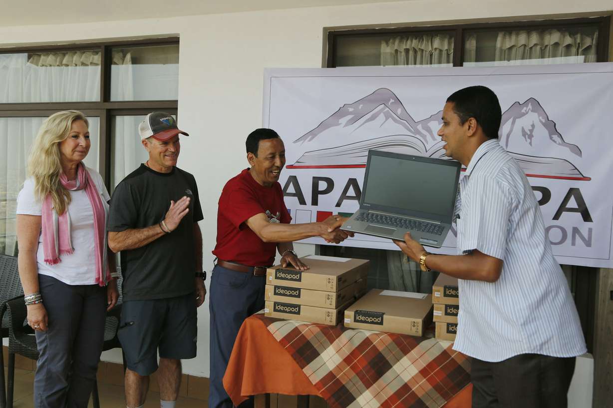 In this May 9, 2019, photo, Apa Sherpa, center, hands over a computer to Chakra Karki, representative of a school from Dhuske, Okhaldhunga district in Kathmandu, Nepal. Apa Sherpa has stood on top of the world more times than all but one other person. Now he wants to make sure no one feels compelled to follow in his footsteps. (Photo: Niranjan Shrestha, Associated Press)