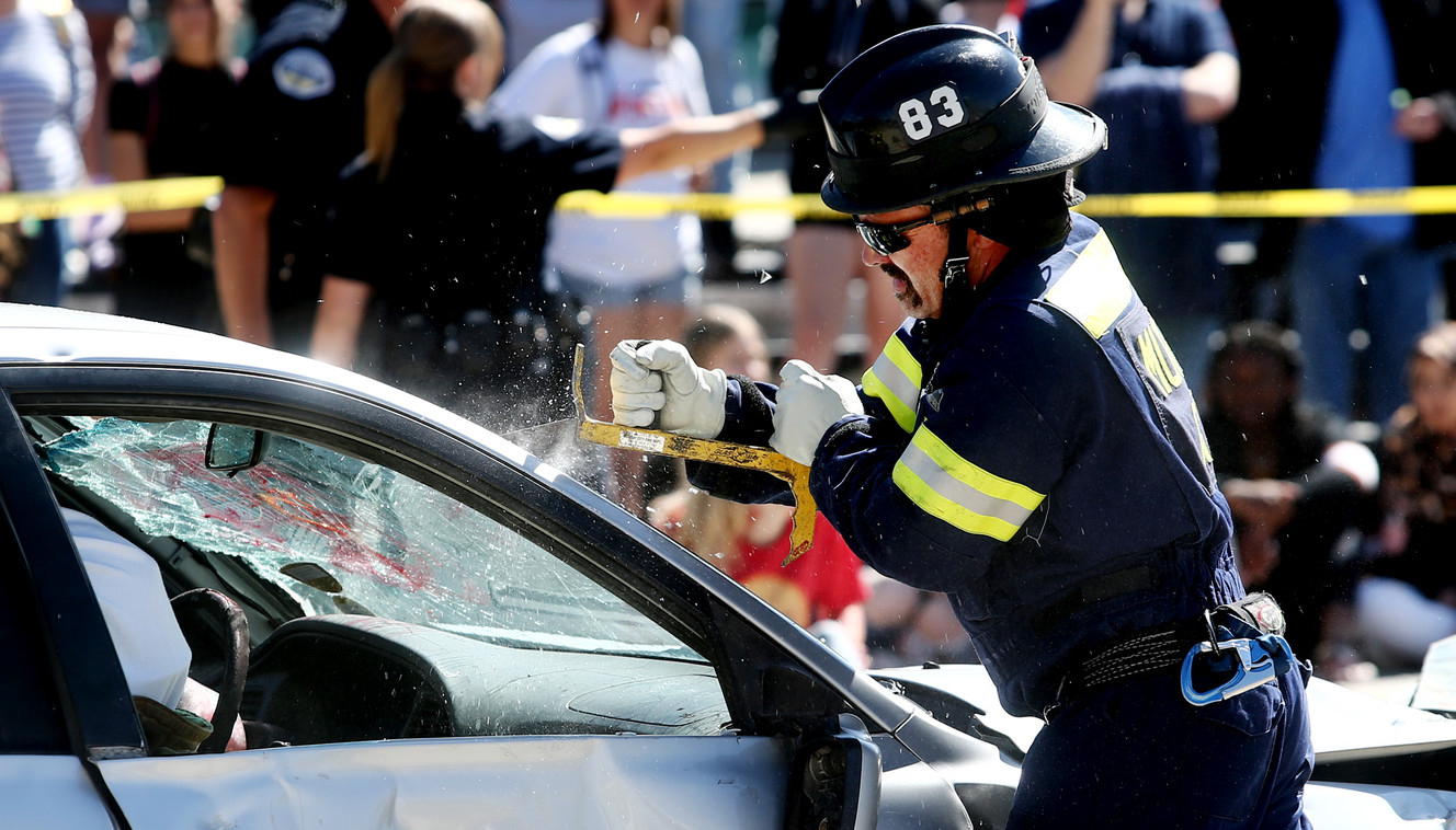 A Murray firefighter cuts out the windshield of a car during a mock car crash at Murray High School on Friday, May 31, 2019. (Photo: Scott G Winterton, KSL)