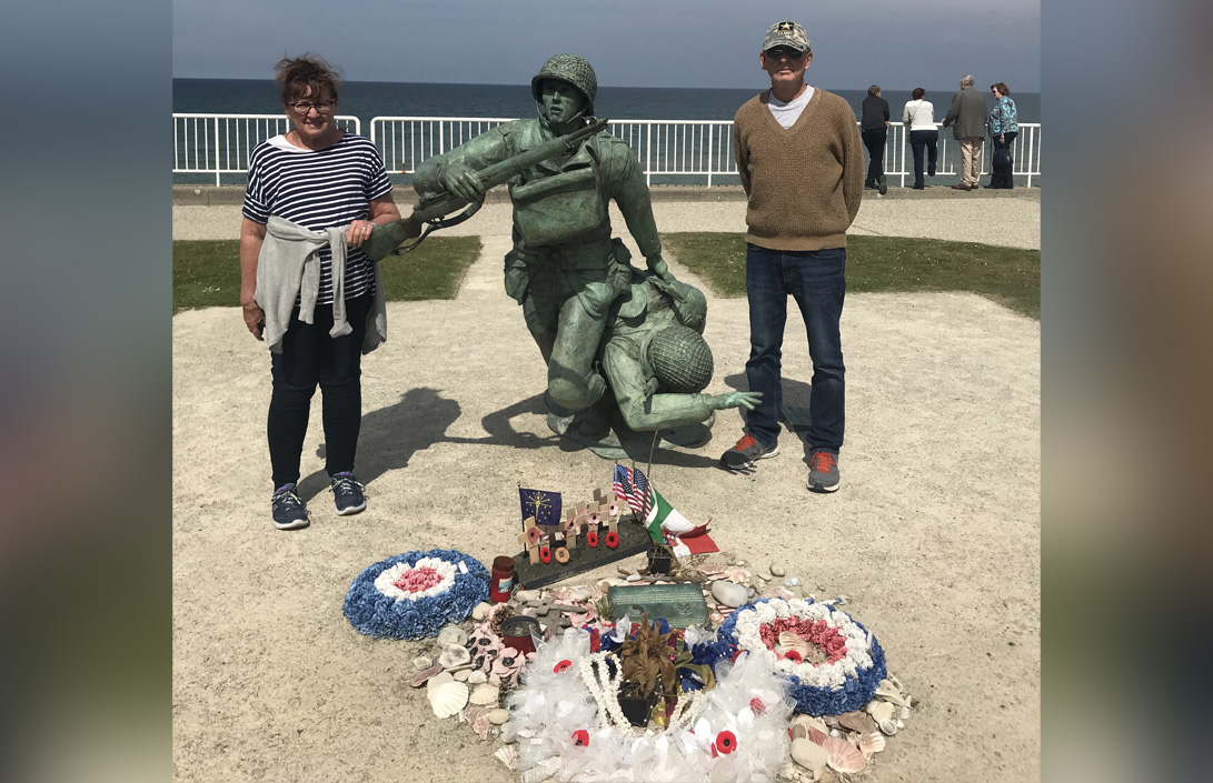 Sharon Murphy, left, and Joel Murphy, right, pose for a photo in front of a statue in Normandy, France, dedicated to the military medics who did all they could to save lives during D-Day. (Photo courtesy Joel Murphy)