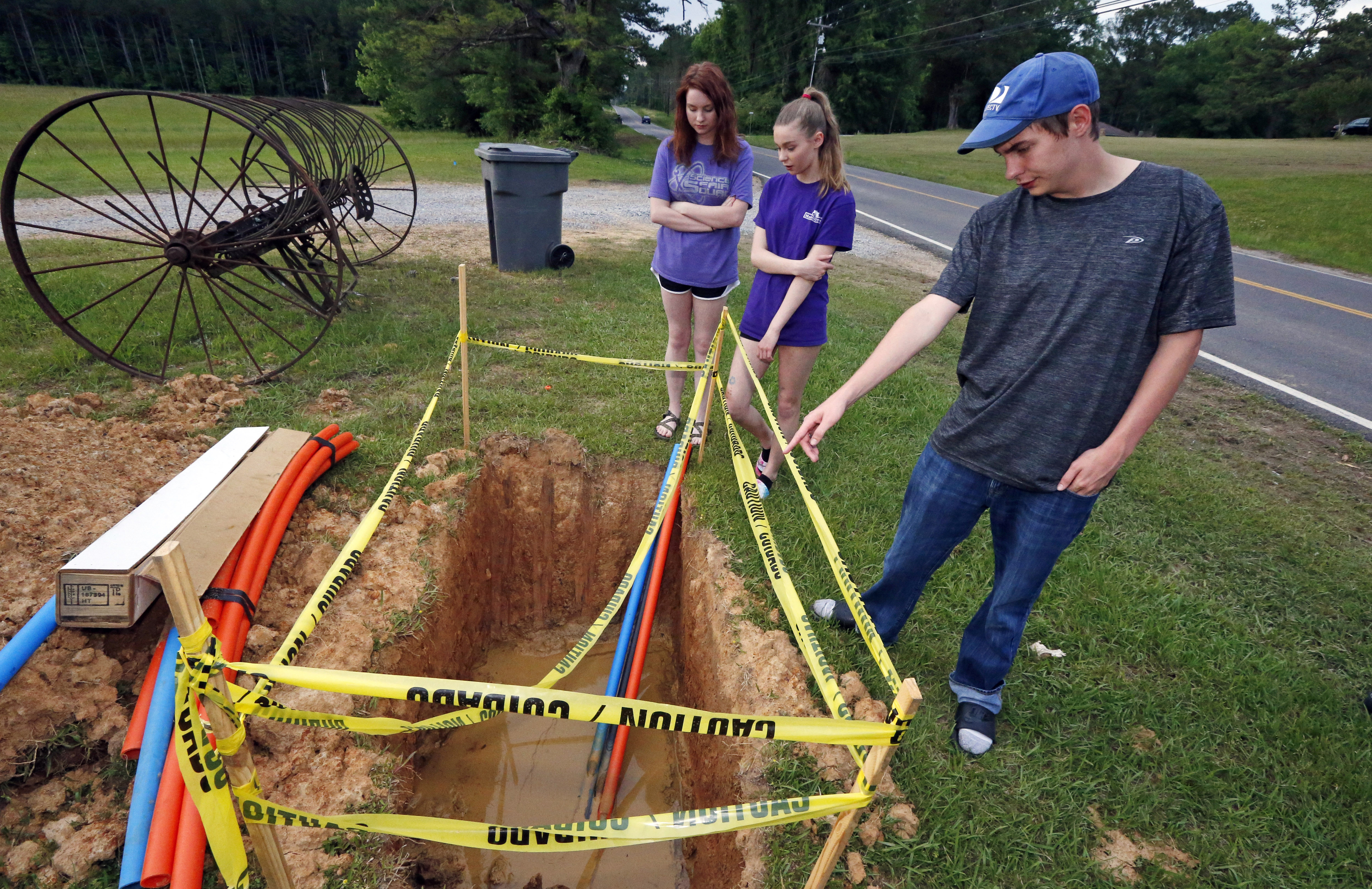 In this May 8, 2019, photograph, Riley Shaw, right, and his youngest sister, Leah, center, and his twin, Abigail, stand around a fiber-optic line that is expected to bring the Shaw family internet service to their home outside Starkville, Miss. Photo: AP Photo