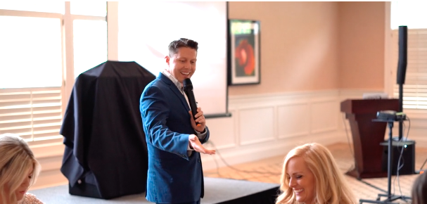 An emcee read off the bachelor's hobbies while he mimed them behind a sheet at the VIP event, Friday, June 7, 2019. (Photo: Courtesy of LDS Matchmakers)