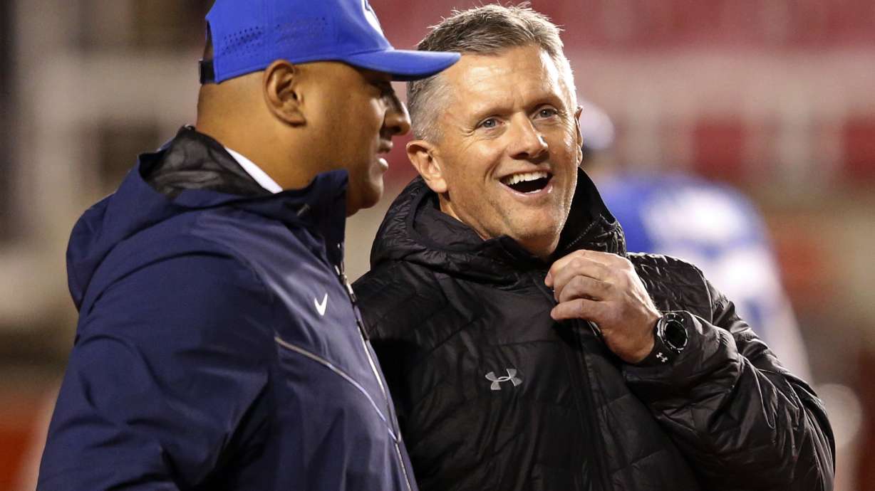 Utah head coach Kyle Whittingham, right, and BYU head coach Kalani Sitake, left, share a laugh before the start of their NCAA college football game Saturday Nov. 24, 2018, in Salt Lake City.