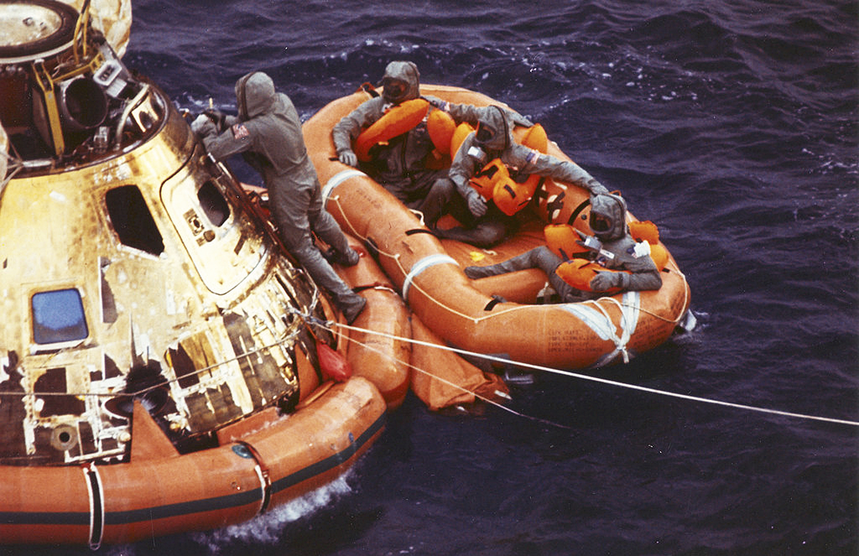 FILE - In this July 24, 1969 photo from the U.S. Navy, Lt. Clancy Hatleberg closes the Apollo 11 spacecraft hatch as astronauts Neil Armstrong, Michael Collins, and Buzz Aldrin, Jr., await helicopter pickup from their life raft after splashdown in the Pacific Ocean, 900 miles southwest of Hawaii, returning to Earth from a successful lunar landing mission. His mission was to decontaminate the astronauts and their command module, Columbia, immediately following splashdown. (Milt Putnam, U.S. Navy via AP)