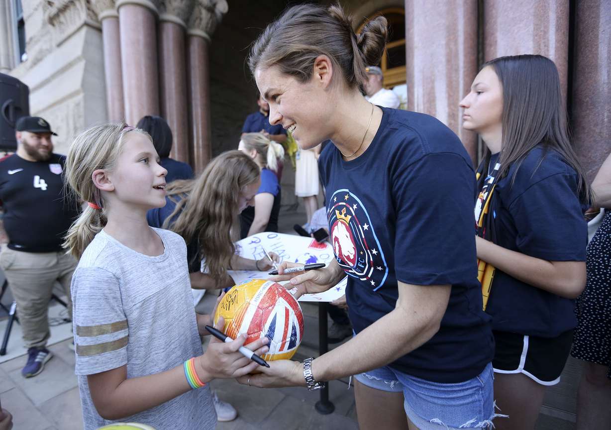 United States women's national soccer team defender Kelley O'Hara signs a soccer ball for Ivy Marquardt outside of the City and County Building in Salt Lake City on Monday, July 22, 2019. (Photo: Kristin Murphy, KSL)