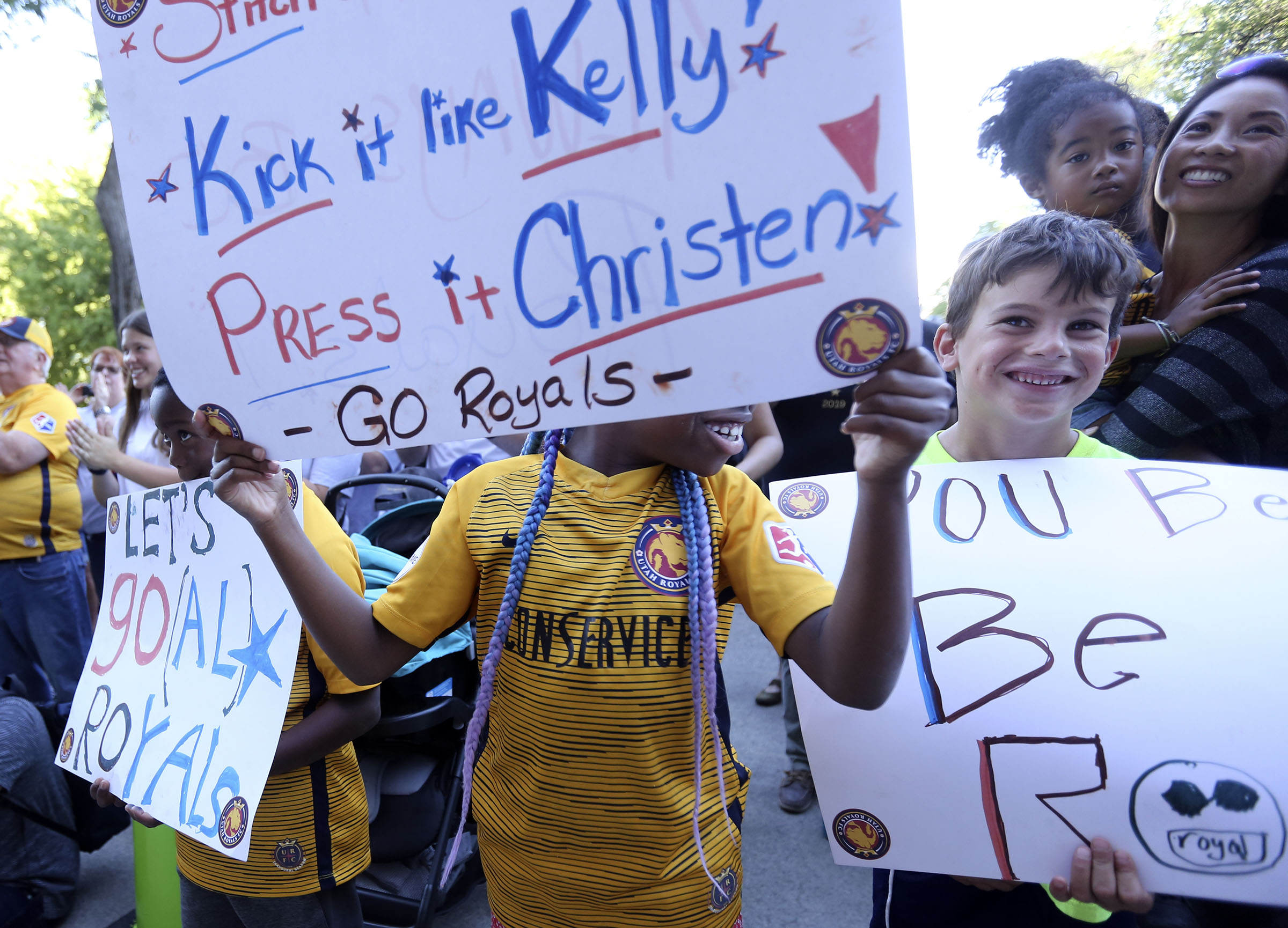 Aziza Landau and Pierce Mendoza hold signs as Salt Lake City Mayor Jackie Biskupski gives United States women's national soccer team athletes Kelley O'Hara, Becky Sauerbrunn, and Christen Press keys to the city outside of the City and County Building in Salt Lake City on Monday, July 22, 2019. (Photo: Kristin Murphy, KSL)