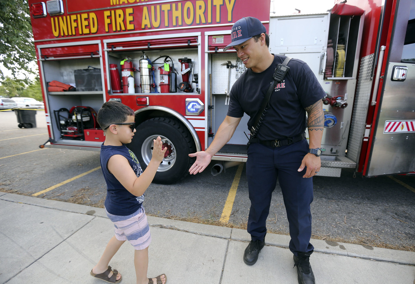 Bentley Miramontes, who wants to be a firefighter, high-fives Unified firefighter Keloni Kamalani during a Night Out Against Crime at Pleasant Green Park in Magna on Monday, Aug. 5, 2019. (Photo: Kristin Murphy, KSL)