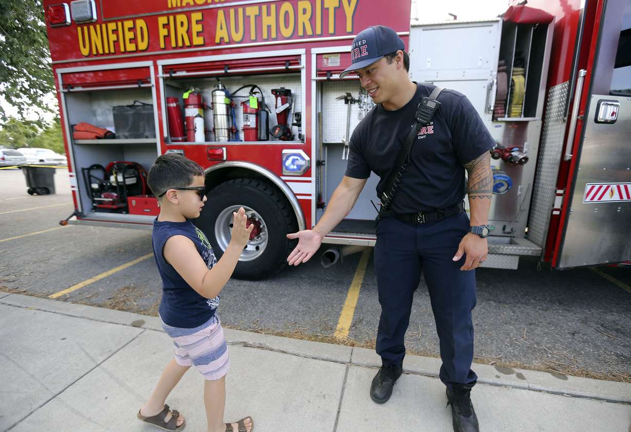 Bentley Miramontes, who wants to be a firefighter, high-fives Unified firefighter Keloni Kamalani during a Night Out Against Crime at Pleasant Green Park in Magna on Monday, Aug. 5, 2019. (Photo: Kristin Murphy, KSL)