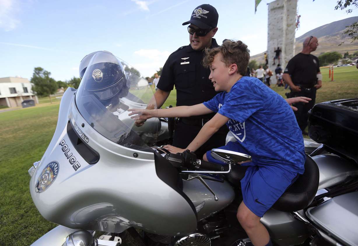 Unified police officer Zack Young shows Brayden Zambos a police motorcycle during a Night Out Against Crime at Pleasant Green Park in Magna on Monday, Aug. 5, 2019. (Photo: Kristin Murphy, KSL)