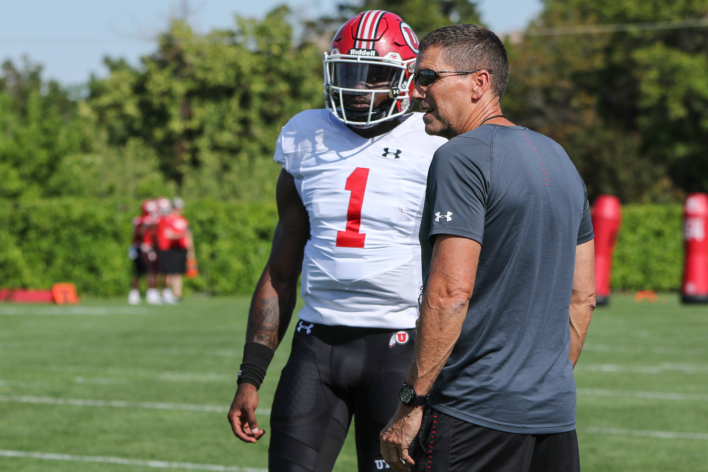 Utah offensive coordinator Andy Ludwig talks to senior quarterback Tyler Huntley during Utah's first practice with full pads on Aug. 5, 2019 in Salt Lake City. (Photo: Courtesy of Utah Athletics)