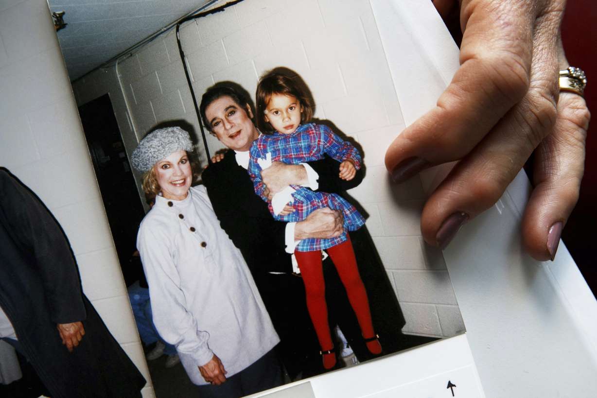 Opera singer Patricia Wulf holds a 1998 photo of herself, left, with opera star Placido Domingo holding her 4-year old daughter after a performance of "Fedora" at the Washington Opera, at her home in rural northern Virginia, on Friday, July 12, 2019. (Jacquelyn Martin, AP Photo)