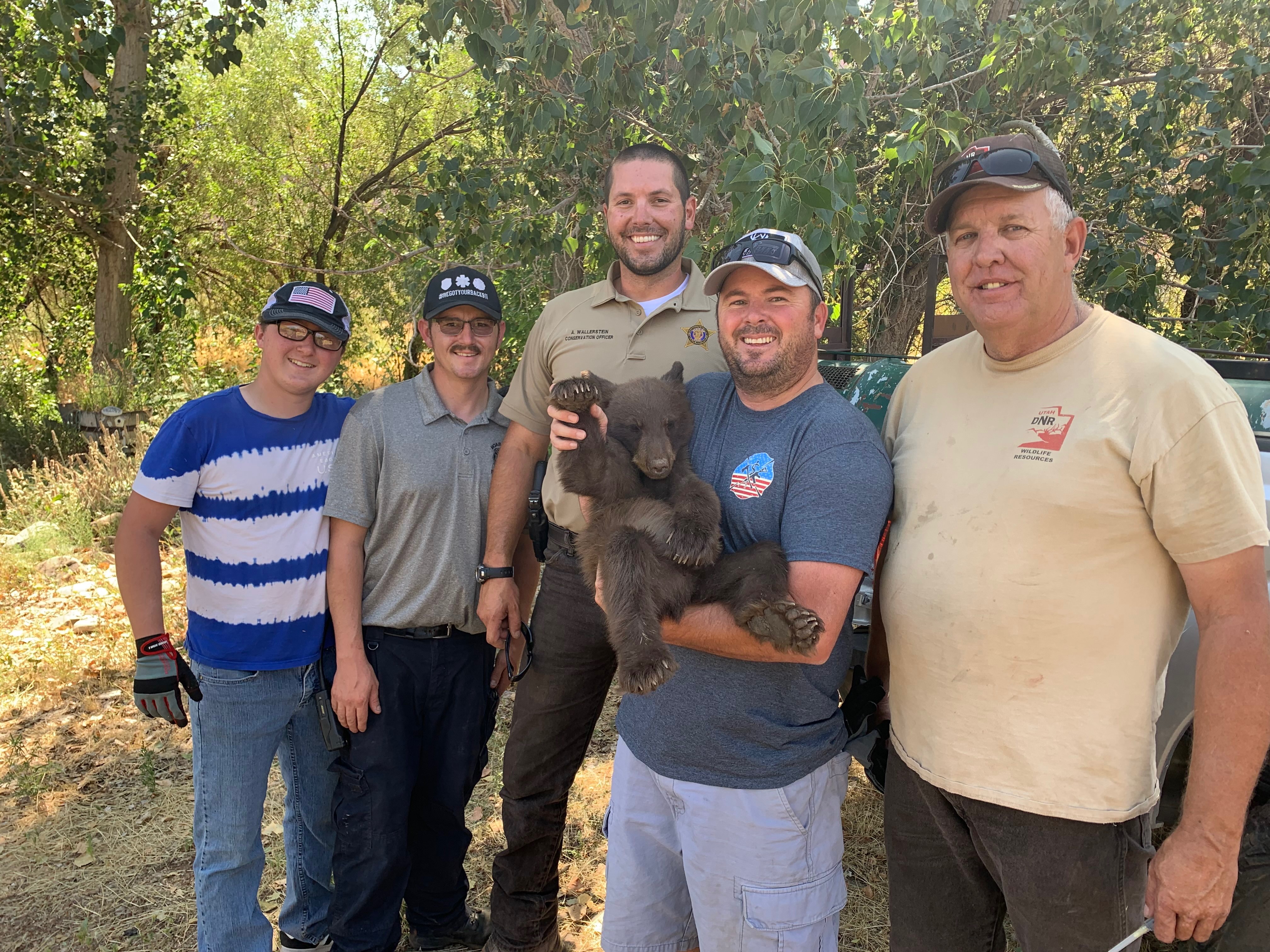 Moab Valley Fire Chief TJ Brewer holds a cub that was removed from a tree, along with its mother and sibling, by wildlife management in the front yard of a Castle Valley home on Friday, Aug. 23, 2019. (Photo: Utah Department of Wildlife Resources)