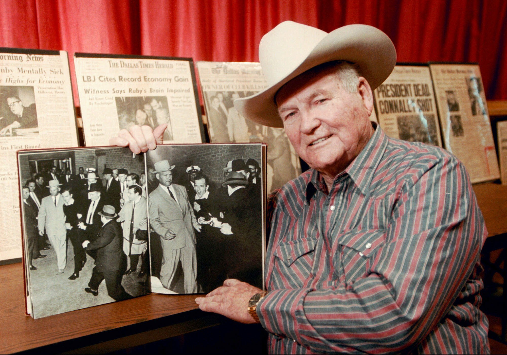 FILE - In this Dec. 11, 1998 file photo, shows Jim Leavelle in Stafford, Kansas holding the iconic 1963 photograph, as he escorted Lee Harvey Oswald moments before he is shot in Dallas. Leavelle, the longtime Dallas lawman has died, Thursday, Aug. 29, 2019. He was 99. (Sandra J. Milburn, The Hutchinson News via AP)