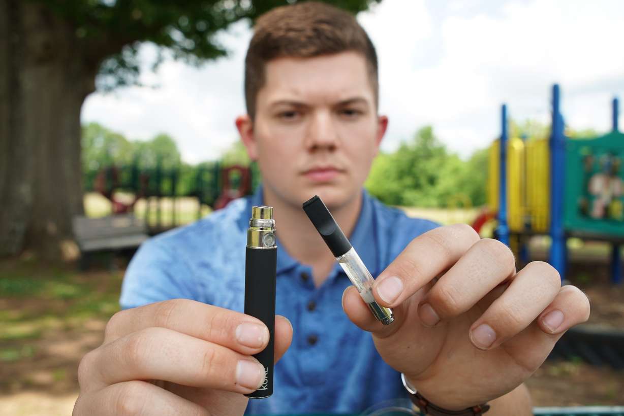 Jay Jenkins holds a Yolo! brand CBD oil vape cartridge alongside a vape pen at a park in Ninety Six, S.C., on Wednesday, May 8, 2019. (Allen G. Breed, AP Photo)