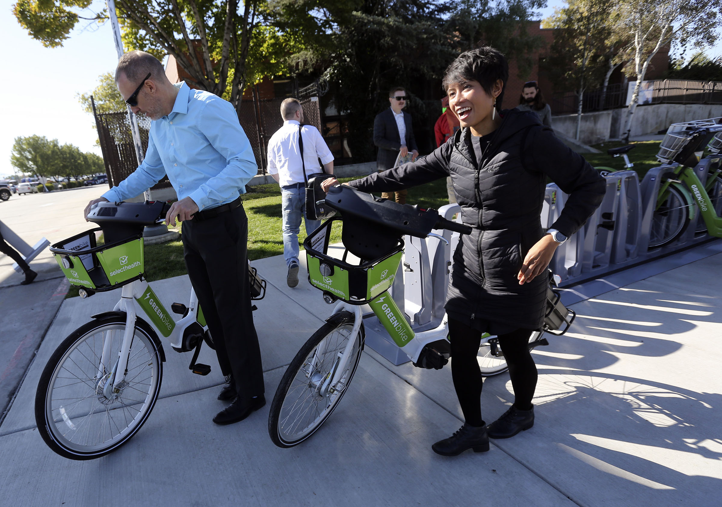 Jory Johner, Wasatch Front Regional Council long-range planning director, and Nikki Navio, Wasatch Front Regional Council transportation planner, get ready to take electric GREENbikes back to their office after attending a press conference a press conference in South Salt Lake on Thursday, Oct. 3, 2019, about the expansion of the bicycle sharing program. The bikes' availability has been expanded to cover 8 square miles, from 2100 South to North Temple and 700 West to 900 East. (Kristin Murphy, KSL)