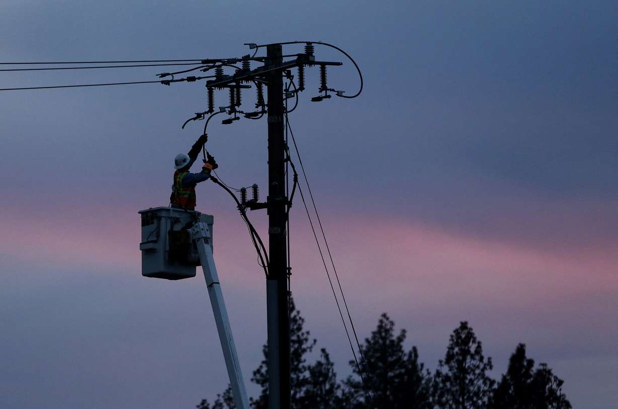 In this Nov. 26, 2018, file photo, a Pacific Gas & Electric lineman works to repair a power line in fire-ravaged Paradise, Calif. (AP Photo/Rich Pedroncelli, File)