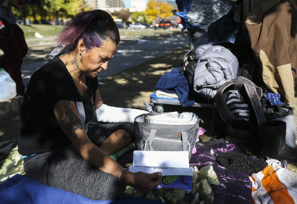 Natalie Vasquez looks through an adult coloring book as she gets her hair colored on the Library Square lawn in Salt Lake City on Monday, Oct. 14, 2019. Vasquez has tried to get a bed at the new women’s shelter several times but has been told they are at capacity each time. (Photo: Colter Peterson, KSL)
