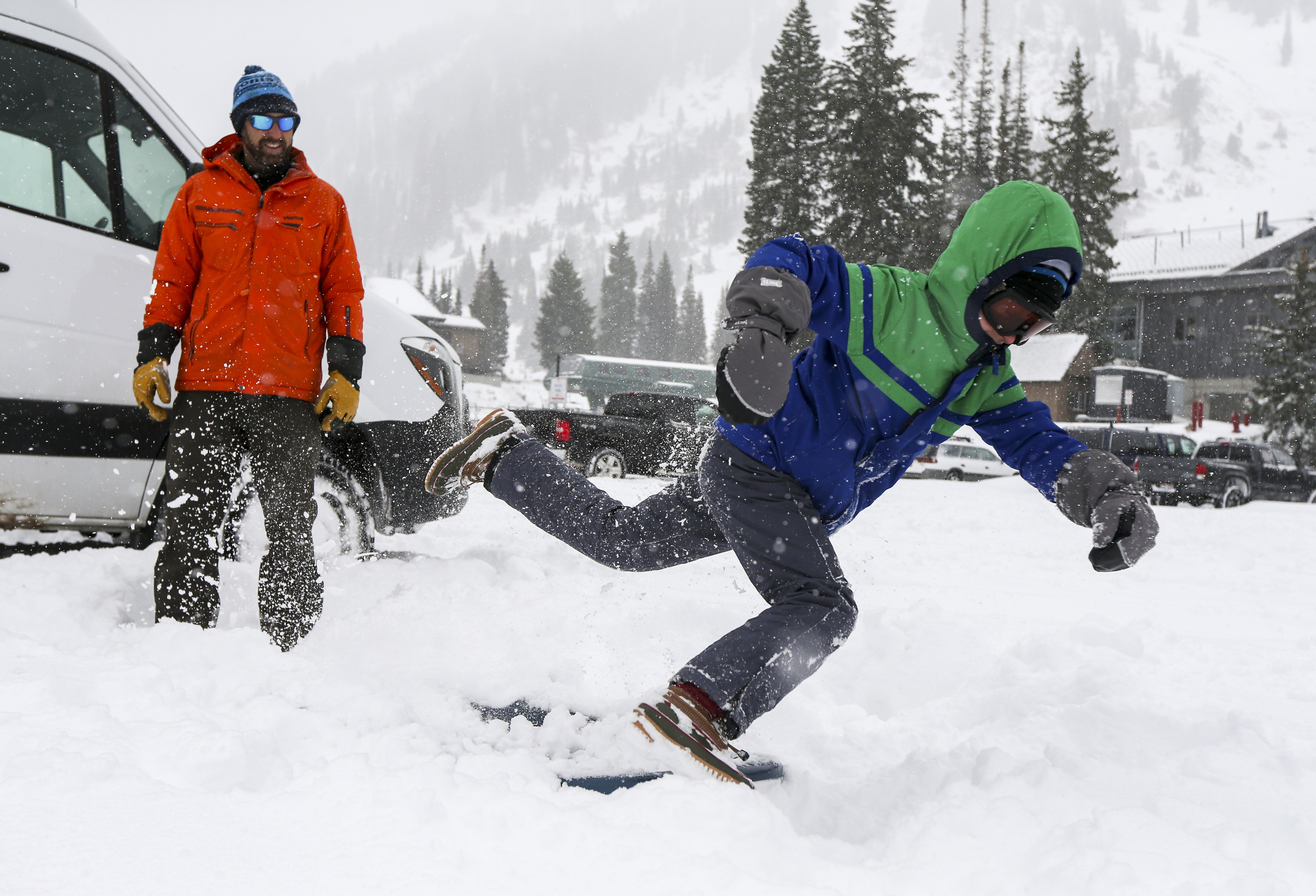 Seth Arens, left, watches as his son Quinn Arens, 8, purposely slips on his sled into the snow while he waits for the family to get ready to sled at the Wildcat base area at Alta Ski Resort in Little Cottonwood Canyon as they enjoy the first substantial snowfall of the year on Sunday, Oct. 20, 2019. (Colter Peterson, KSL)