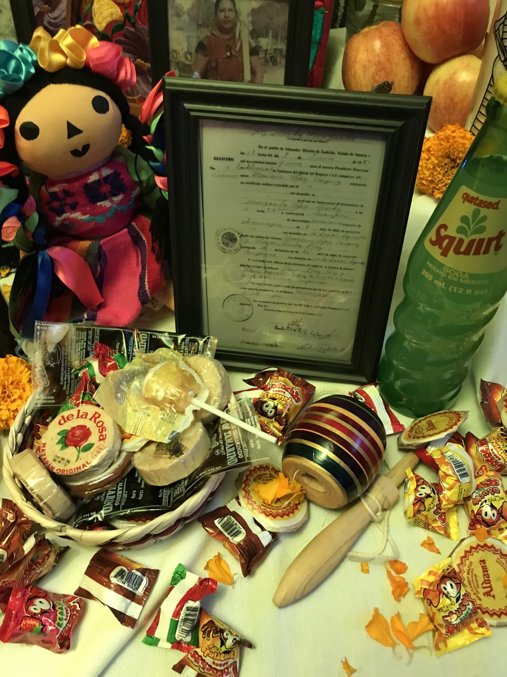 A death certificate displayed alongside traditional Mexican candies, a doll, soda and toys on the Carrascos altar at Thanksgiving Point on Saturday, Oct. 26. (Photo: Madison Carrasco)