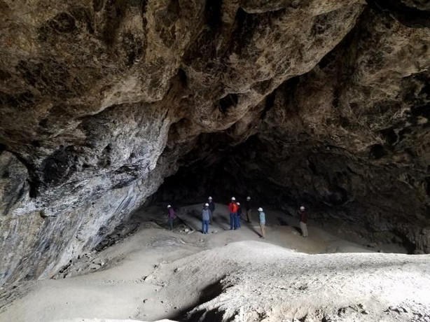 Visitors to Jukebox Cave look at its historic dance floor. The cave got its name from the cement dance floor airmen from nearby Wendover Airbase poured to hold dances in a place out of the intense desert heat. (Utah Division of Parks and Recreation)