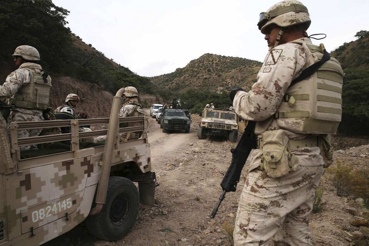 Heavily armed Mexican authorities guard a caravan of friends and relatives of the LeBaron family as they arrive at the site where nine U.S. citizens, three women and six children related to the extended LeBaron family, were slaughtered when cartel gunmen ambushed three SUVs along a dirt road near Bavispe, at the Sonora-Chihuahua border, Mexico, Wednesday, Nov 6, 2019. (AP Photo/Marco Ugarte)