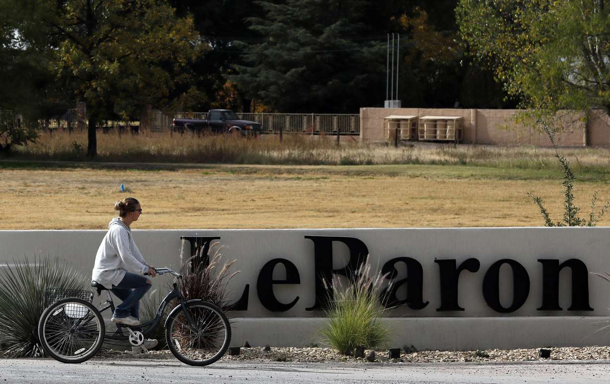 A woman cycles past a sign announcing the Colonia LeBaron, a community settled by members of the extended LeBaron family in Chihuahua state in northern Mexico, Wednesday, Nov. 6, 2019. (AP Photo/Marco Ugarte)