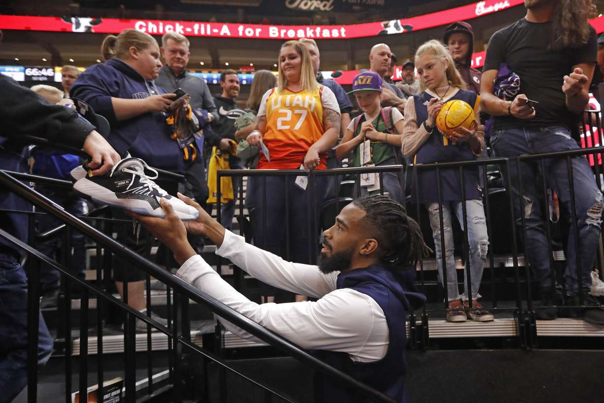 Utah Jazz guard Mike Conley signs the shoes of a fan following practice before the start of an NBA basketball game against the Philadelphia 76ers Wednesday, Nov. 6, 2019, in Salt Lake City. (AP Photo/Rick Bowmer)