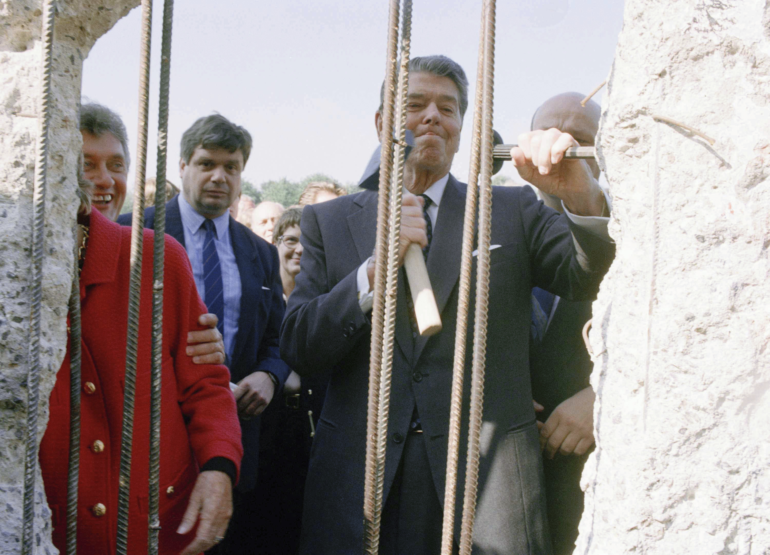 In this Wednesday, Sept. 12, 1990 file photo, former U.S. President Ronald Reagan, center, uses a hammer and chisel on the defunct Berlin Wall to take symbolic swings at the old Cold War barrier. Photo: AP Photo, File