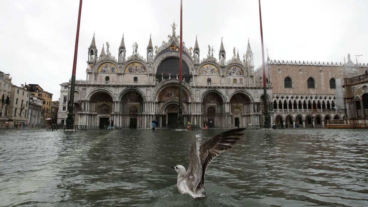 Tourists, Venetians slosh through flooded lagoon city