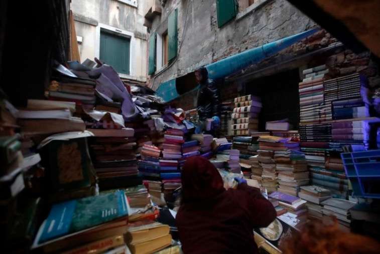 Volunteers pile up damaged books from renowned bookstore "Acqua Alta" (High Water) after flooding in Venice, Italy, Friday, Nov. 15, 2019. Exceptionally high tidal waters returned to Venice on Friday, prompting the mayor to close the iconic St. Mark's Square and call for donations to repair the Italian lagoon city just three days after it experienced its worst flooding in 50 years. (AP Photo/Luca Bruno)