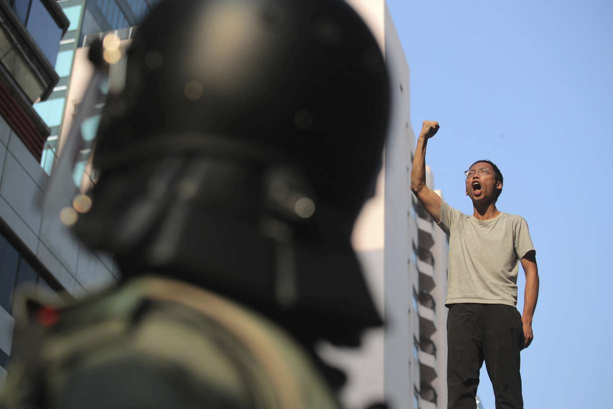 A man on top of a bridge raises his fist shouting slogans as he's stopped by police while trying to escape the Hong Kong Polytechnic University campus in Hong Kong, Monday, Nov. 18, 2019. Hong Kong police using tear gas and rubber bullets fought off protesters Monday as they tried to break through a police cordon that is trapping hundreds of them on a university campus. (Kin Cheung, AP Photo)