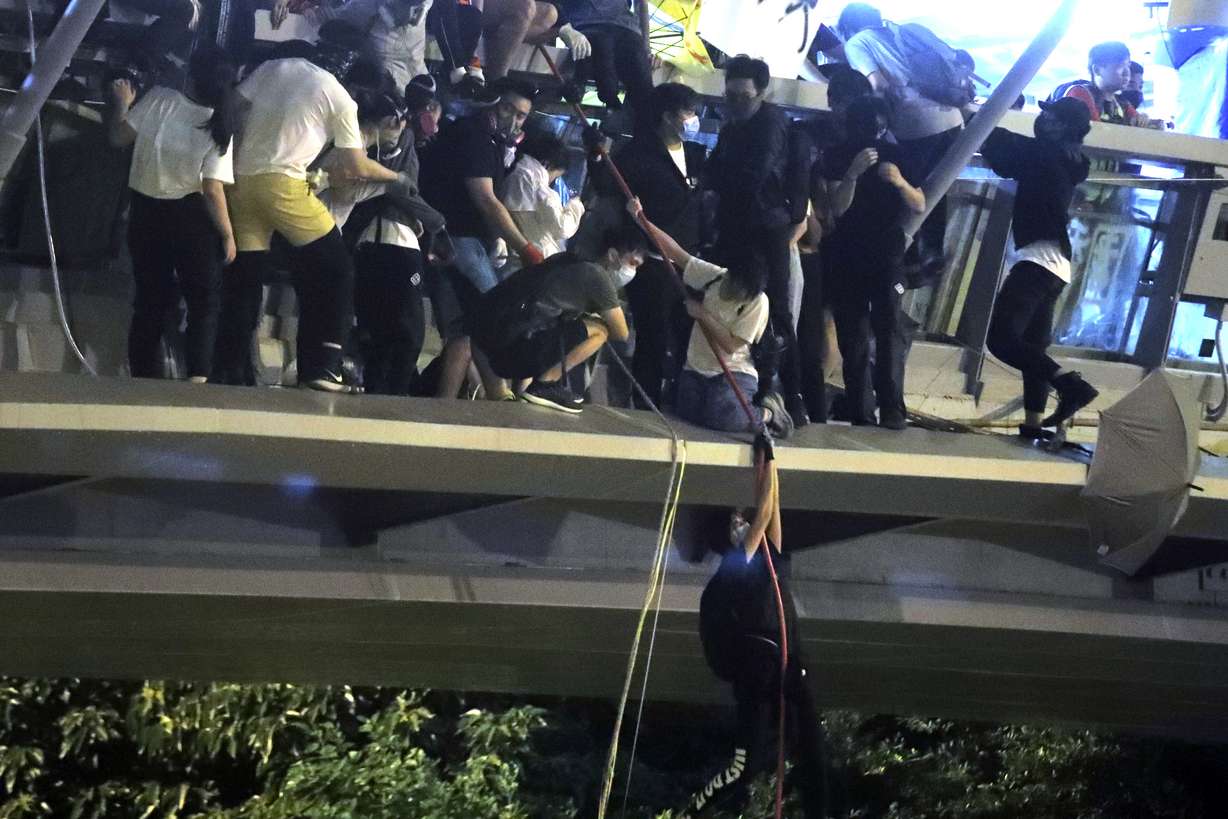 Protestors use a rope to lower themselves from a pedestrian bridge to waiting motorbikes in order to escape from Hong Kong Polytechnic University and the police in Hong Kong, Monday, Nov. 18, 2019. As night fell in Hong Kong, police tightened a siege Monday at a university campus as hundreds of anti-government protesters trapped inside sought to escape. (Kin Cheung, AP Photo)