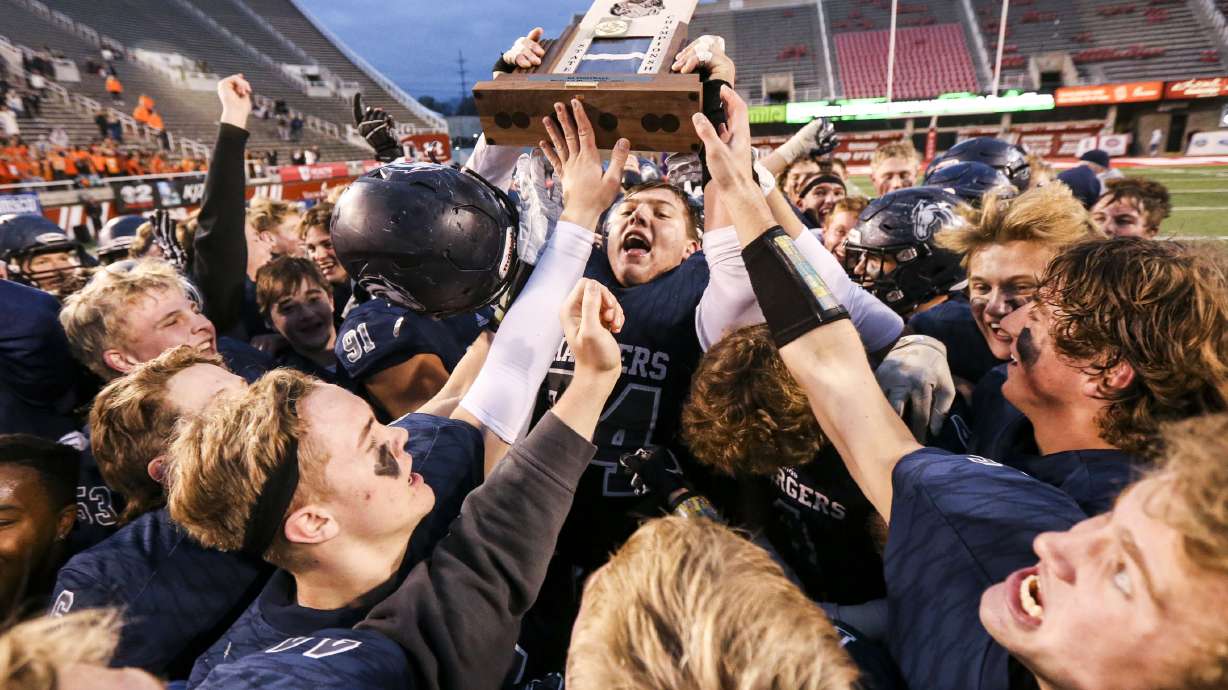 Corner Canyon's Jackson Light (74) hoists the state championship trophy after Corner Canyon rolled over American Fork 49-14 in the 6A state high school football game at Rice-Eccles Stadium in Salt Lake City on Friday, Nov. 22, 2019.