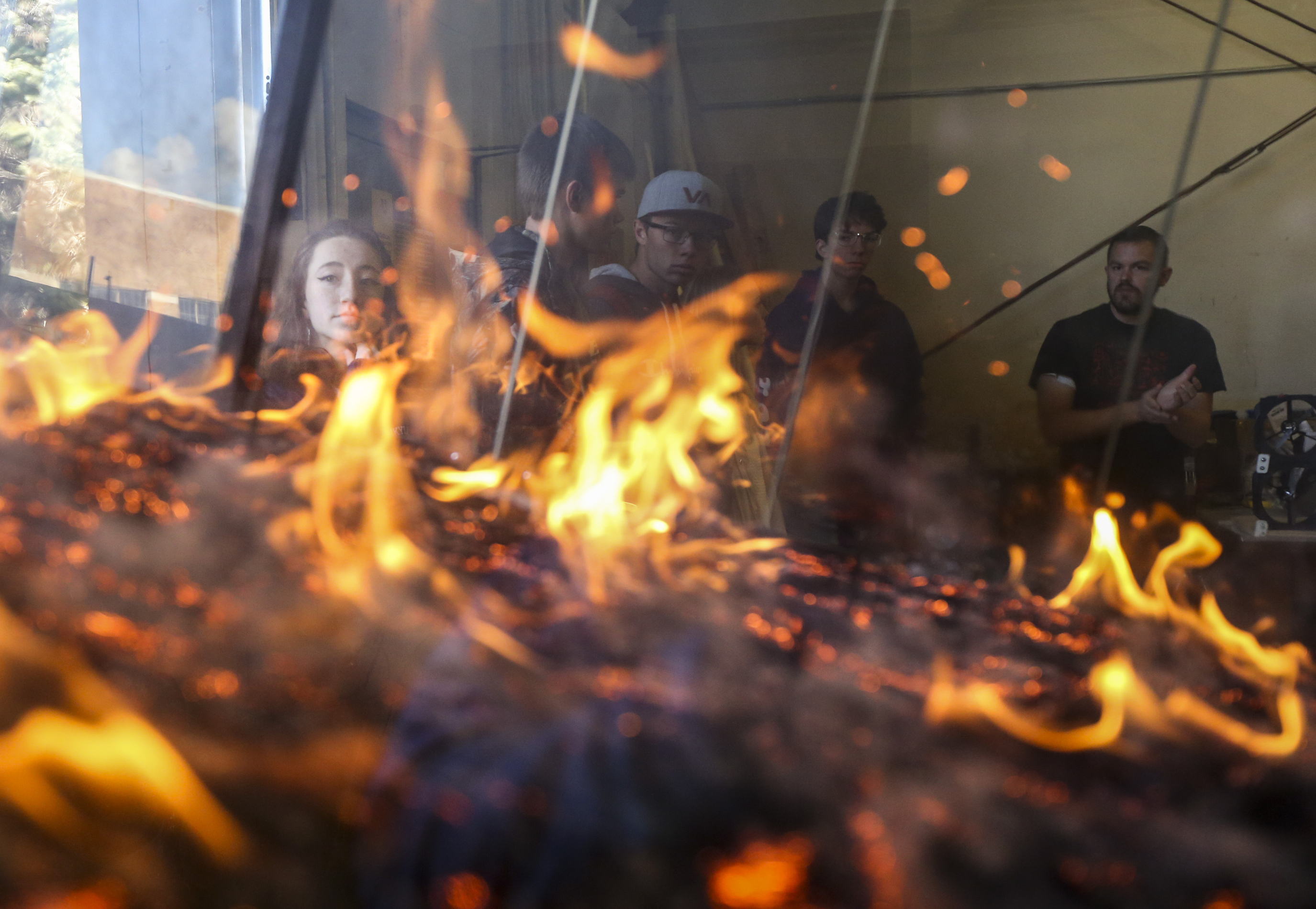 Sixteen-year-old Grace Fearnley, left, and other high school students watch a fire burn in a wildfire modeling machine while Walt Sorensen, right, talks about his research using the chamber during the University of Utah's annual Engineering Day event in the Environmental Fluid Dynamics Laboratory on campus in Salt Lake City, Saturday, Nov. 23, 2019. More than 600 students from around the nation registered for the event that gives parents and students an inside look into the different areas of engineering study offered at the university. (Colter Peterson, KSL)