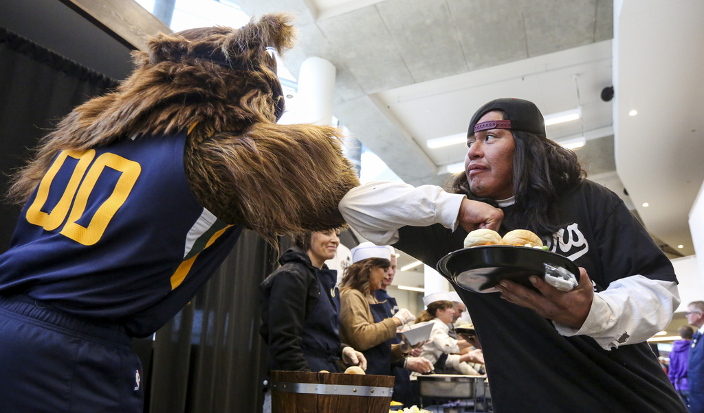 Julian, right, bumps elbows with the Jazz Bear after receiving his Thanksgiving meal during the 21st annual "We Care - We Share" event for the homeless and low-income individuals at the Vivint Smart Home Arena in Salt Lake City on Monday, Nov. 25, 2019. (Photo: Colter Peterson, KSL)