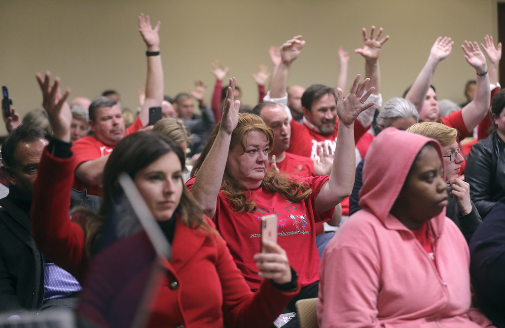 Audience members, many in Red for Ed shirts, raise their hands in support of a public commenter during a Tax Restructuring and Equalization Task Force meeting in the House Building on the state Capitol campus in Salt Lake City on Monday, Nov. 25, 2019. (Photo: Kristin Murphy, KSL)
