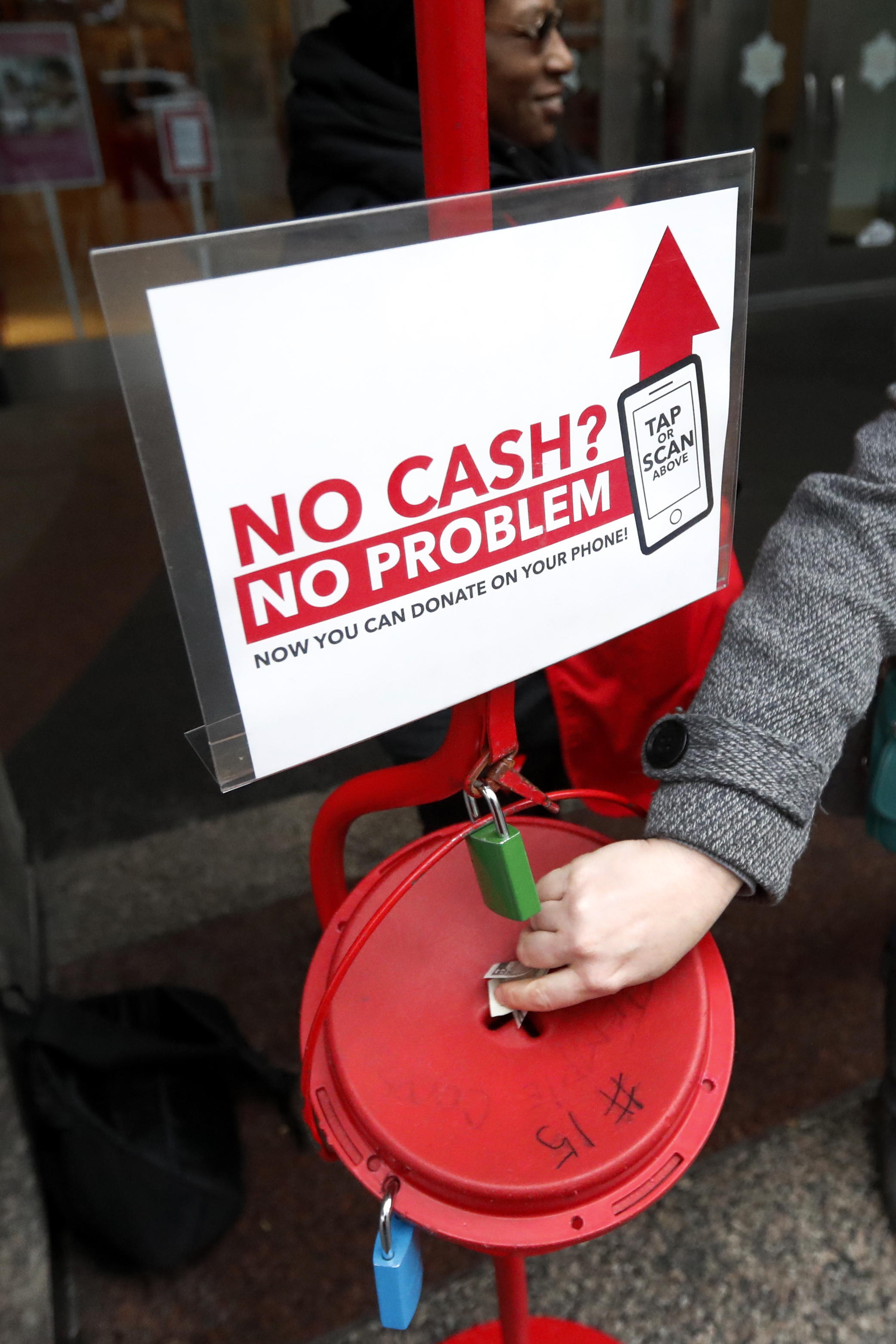 In this Friday, Nov. 15, 2019, photo, a shopper donates cash to the Salvation Army's annual holiday red kettle campaign, with a reminder that mobile contributions are also excepted on Chicago's Magnificent Mile. Photo: Charles Rex Arbogast, AP Photo