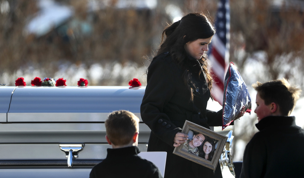 McKenzie Norman Fuchigami, wife of Chief Warrant Officer 2 Kirk T. Fuchigami Jr., holds the American flag that was draped over her husband’s casket and a photo of her and her husband during graveside services at the Brigham City Cemetery on Monday, Dec. 9, 2019. (Photo: Steve Griffin, KSL)
