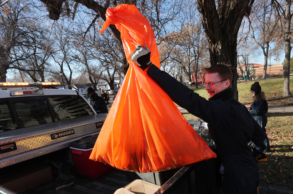 Keith Neijstrom, an environmental health technician, puts a bag of trash into the back of a truck as health department officials, Utah Highway Patrol troopers and Salt Lake City police officers clean up a homelss camp in Salt Lake City on Tuesday, Dec. 10, 2019. (Photo: Scott G. Winterton, KSL)