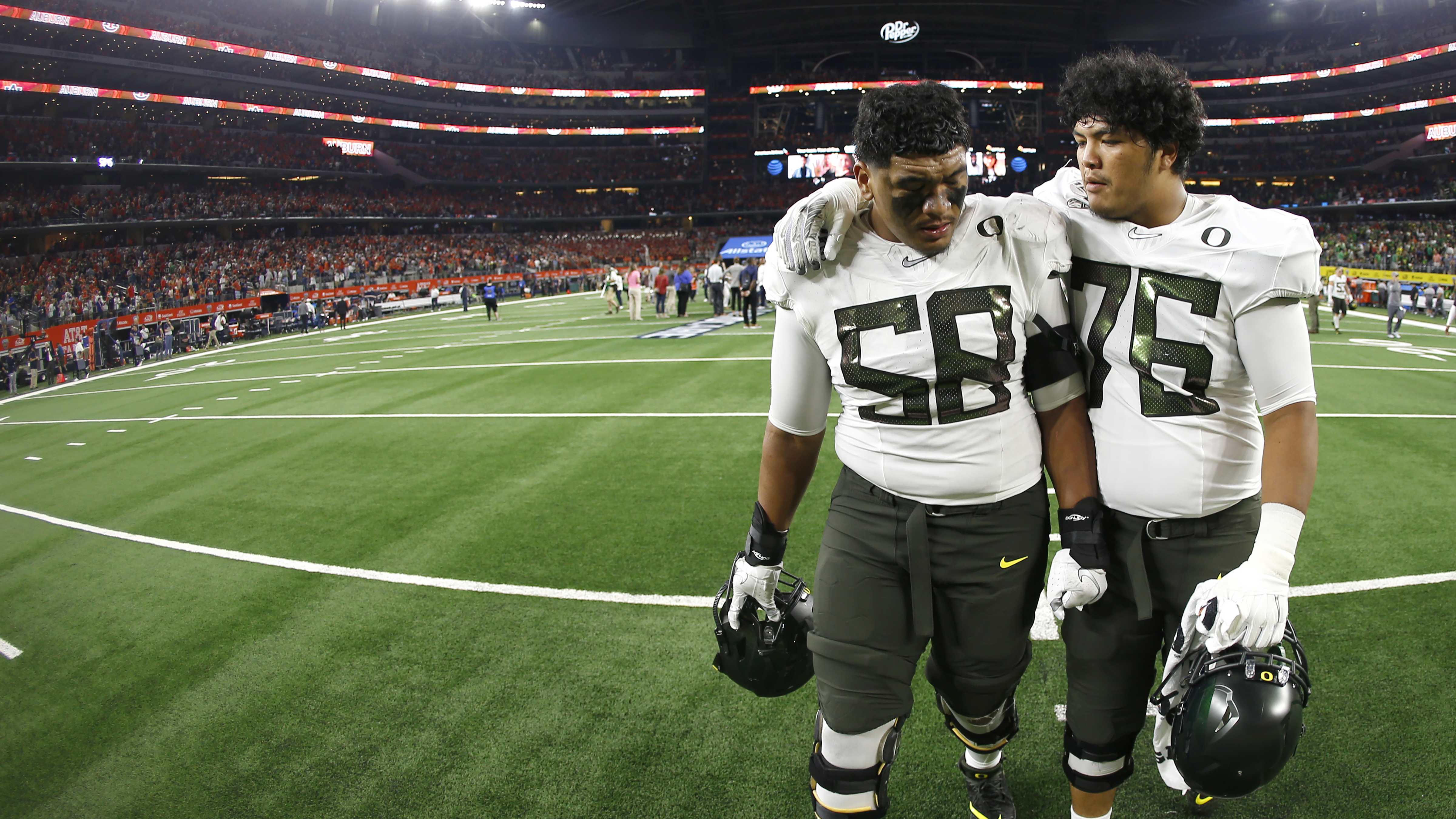 Oregon offensive linemen Penei Sewell (58) and Jonah Tauanu'u (76) walk off the field following the team's loss to Auburn following an NCAA college football game Saturday, Aug. 31, 2019, in Arlington, Texas. Auburn won 27-21. (AP Photo/Ron Jenkins)